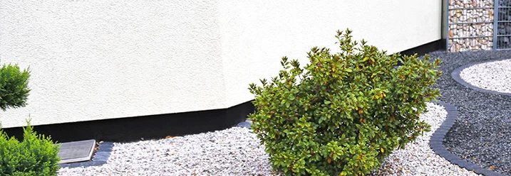 Hauswand mit Kies und Busch